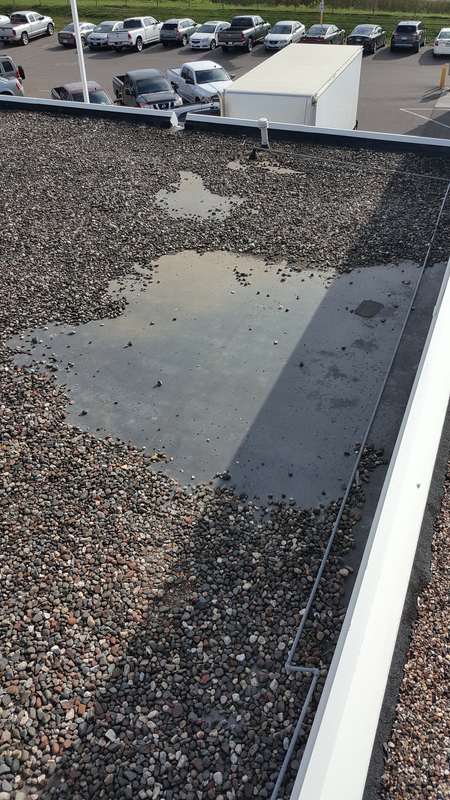 Ponding water on the old gravel roof at Forest Lake Chrysler Jeep Dodge, in Forest Lake, before Repair King replaced it