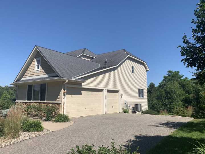 Side and garage of a two-story Rockford, MN home with gray shingles and cream siding, photographed by Repair King in July 2020