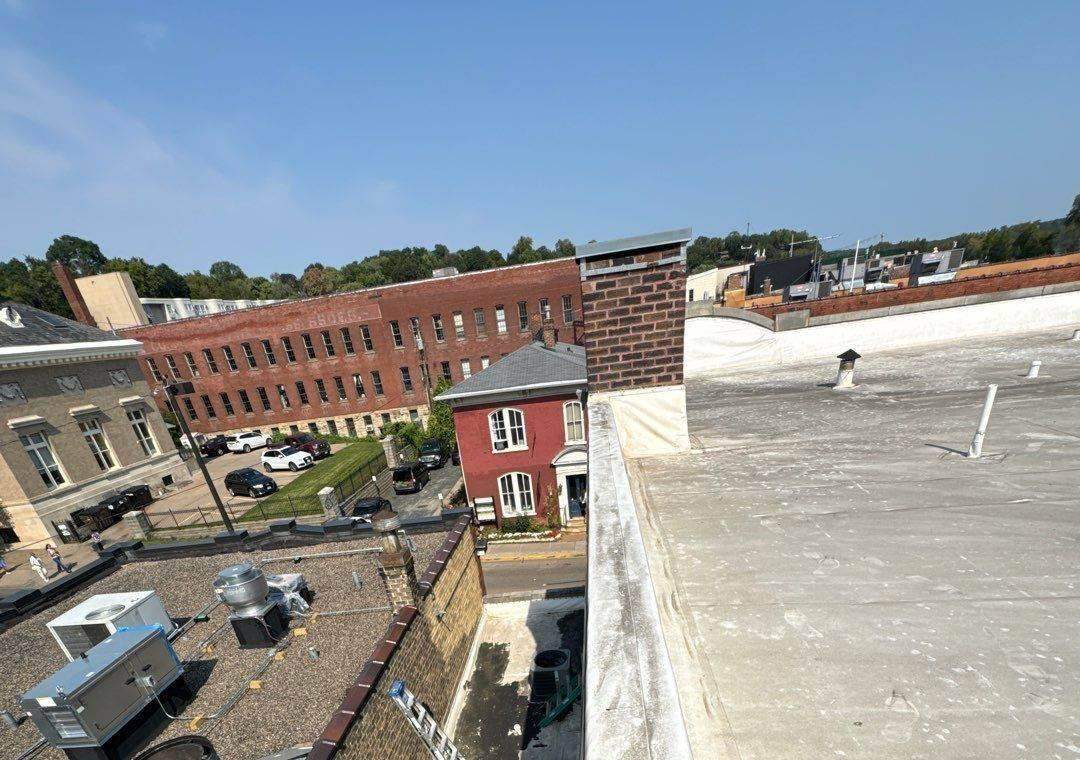 View from the parapet of 106 South Main Street down onto downtown Stillwater, MN rooftops and brick buildings during Repair King's September 2024 roof inspection