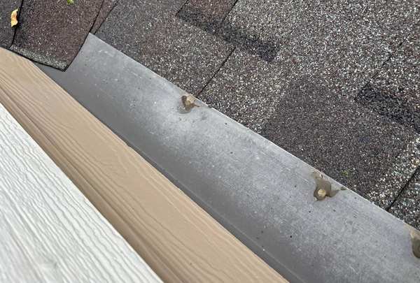 Hail dents in metal roof-to-wall flashing next to siding on a Woodbury home, September 2025