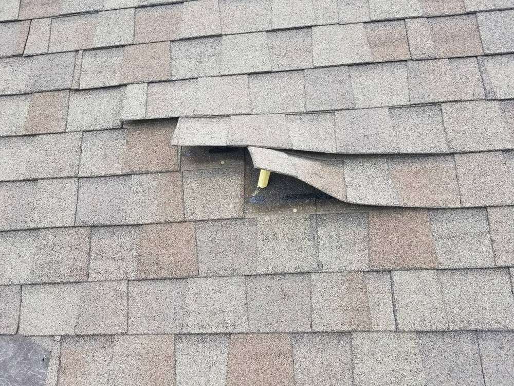 Creased, wind-lifted shingle tabs on the Owatonna Country Club clubhouse roof in Owatonna, MN