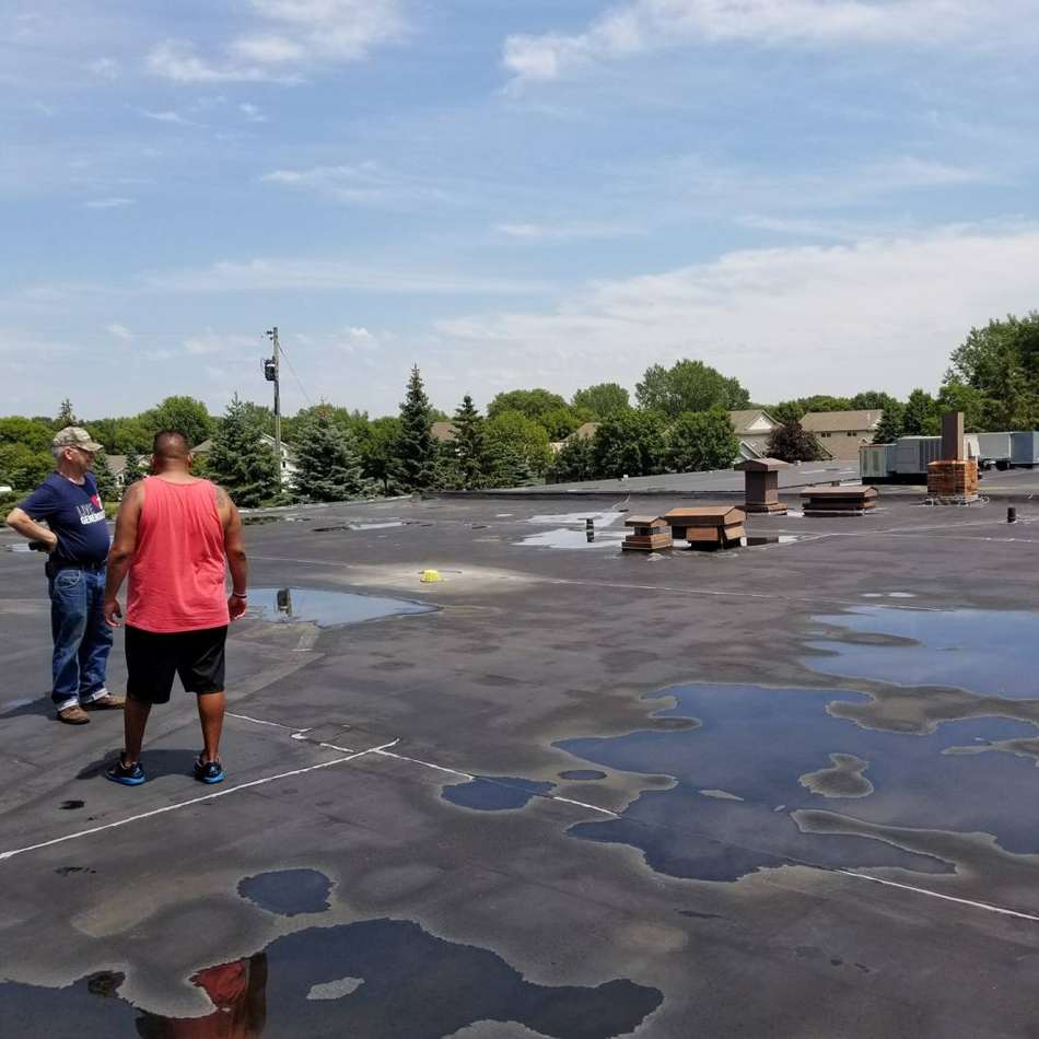 Repair King team walking the ponded flat rubber roof at King of Glory Lutheran Church in Blaine, MN, July 2017