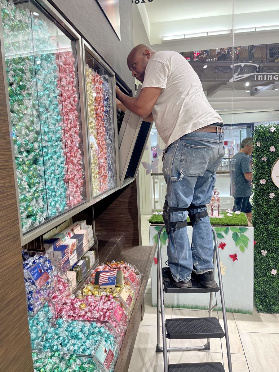Repair King technician adjusting a hinged display case door on a retail wall at Mall of America