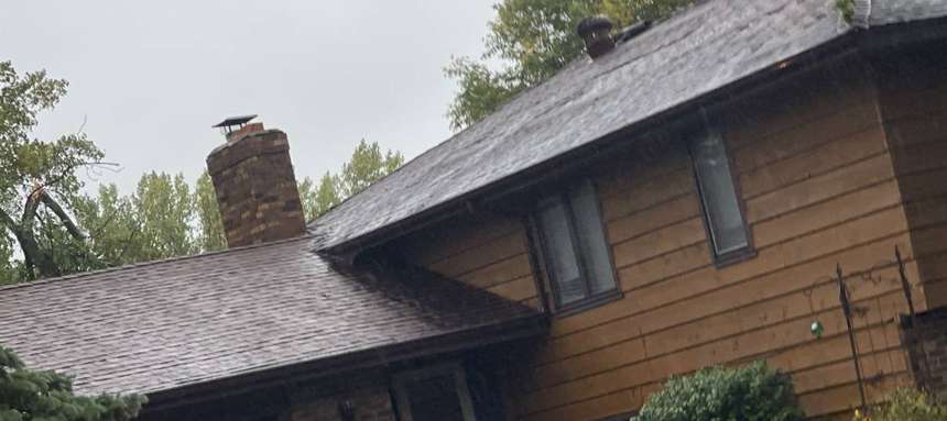 Storm-damaged tree limb over an Apple Valley roofline during an inspection, September 2021