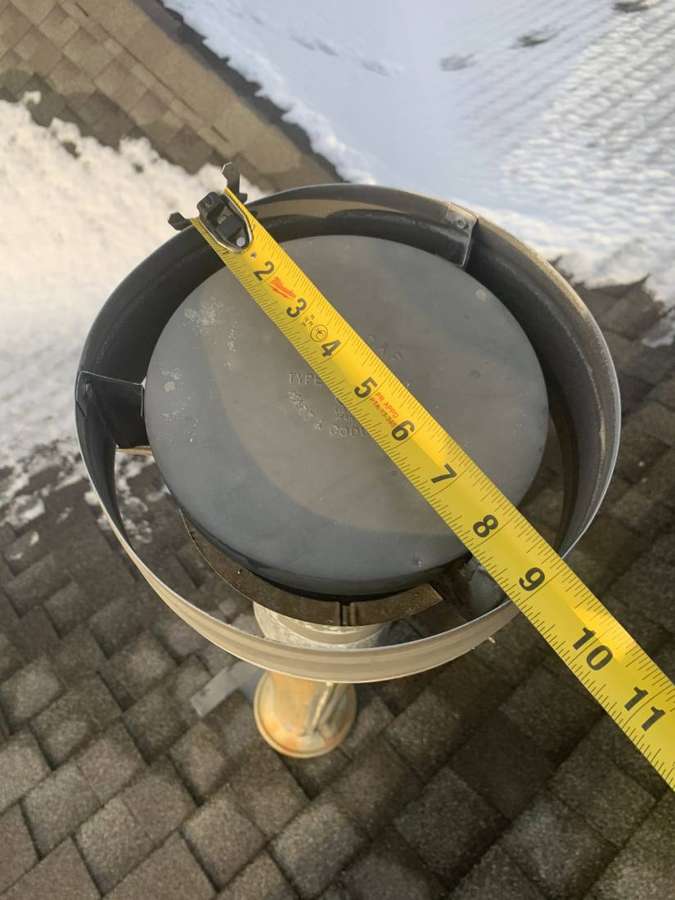 Tape measure across a roof vent cap on a snow-dusted shingle roof at the Penn Place townhomes in North St. Paul, MN