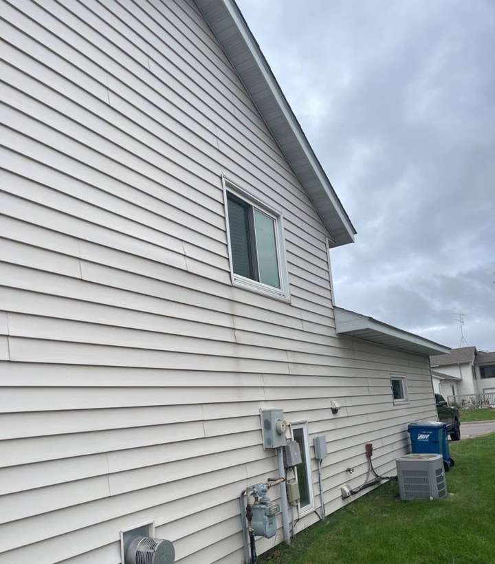 Side of a vinyl-sided home in Sauk Rapids, MN, with its utility meters and window, photographed by Repair King in October 2021