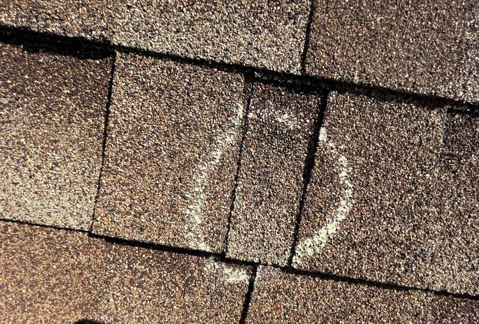 Chalk-marked hail hit on a shingle at Job's House Of Prosperity, August 2025