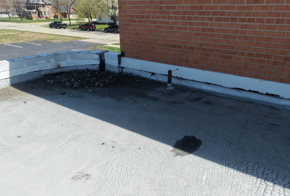 Cracked membrane and parapet flashing on a Lake City commercial flat roof, April 2026