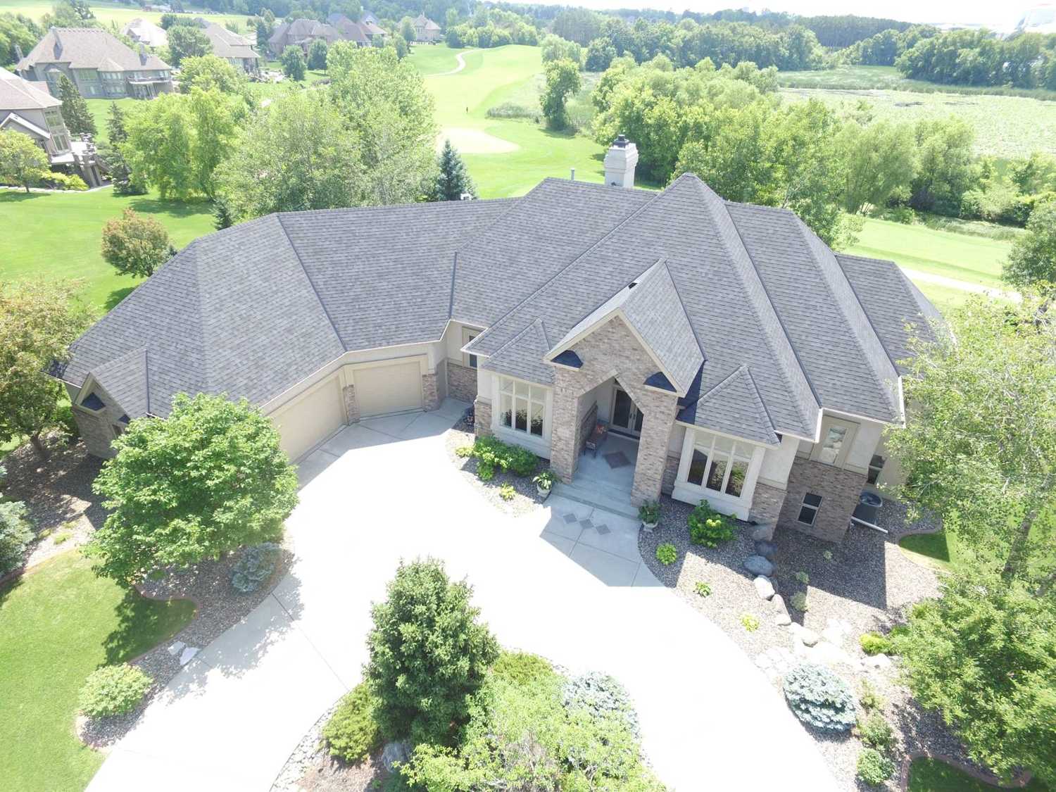 Drone photo of a stucco-and-stone home with a hip roof on a golf course in Prior Lake, MN, documented by Repair King in 2018