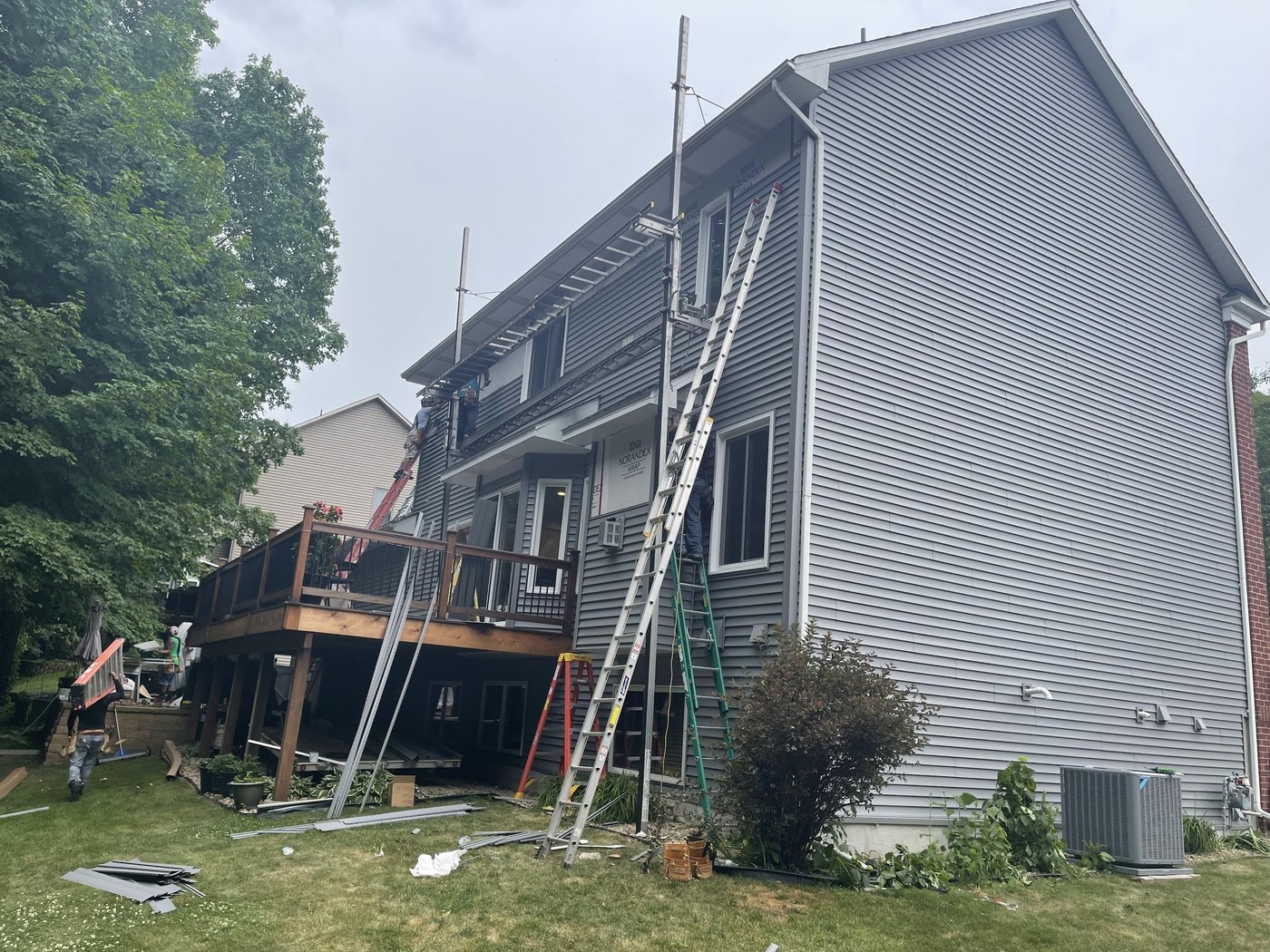 Repair King siding crew on pump-jack staging, installing vinyl siding over house wrap on a Chanhassen two-story