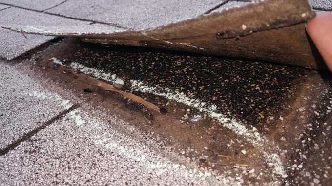 Lifted shingle tab with a torn seal strip, chalk-marked at Red Rock Lodge, Newport