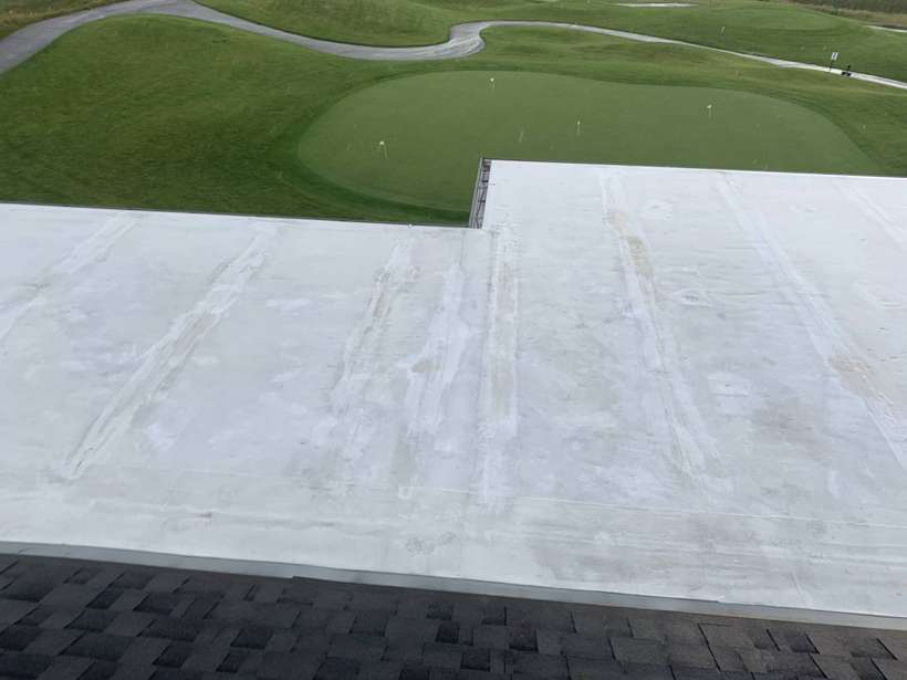White Duro-Last flat roof section beside the shingled roof of the Coyote Moon Grille clubhouse, overlooking a putting green at Territory Golf Club, St. Cloud, MN