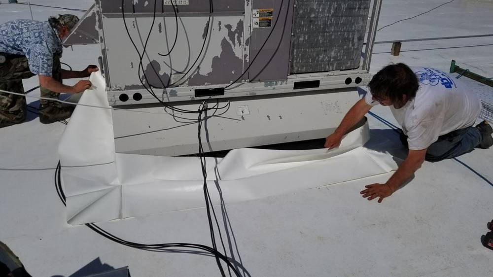 Repair King crew welding white PVC flashing around a rooftop HVAC unit curb on the Forest Lake Chrysler Jeep Dodge roof in Forest Lake, MN
