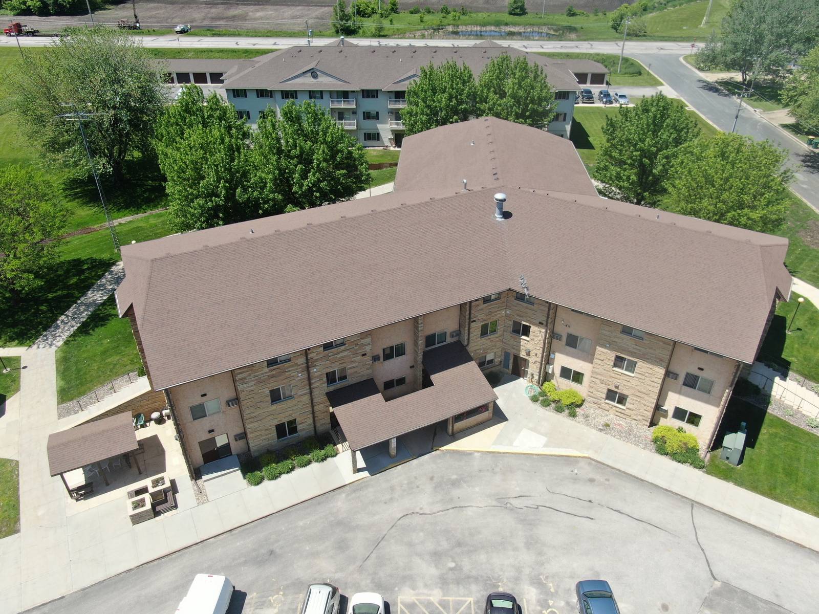 Drone view of the Heritage Estates apartment building in Dodge Center, MN, a three-story stone-faced building with a brown shingle roof, photographed during a Repair King roof inspection