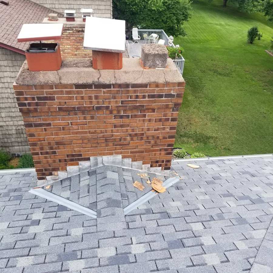 Brick chimney with a cracked, crumbling crown and damaged flashing on a Coon Rapids, MN roof, June 2017