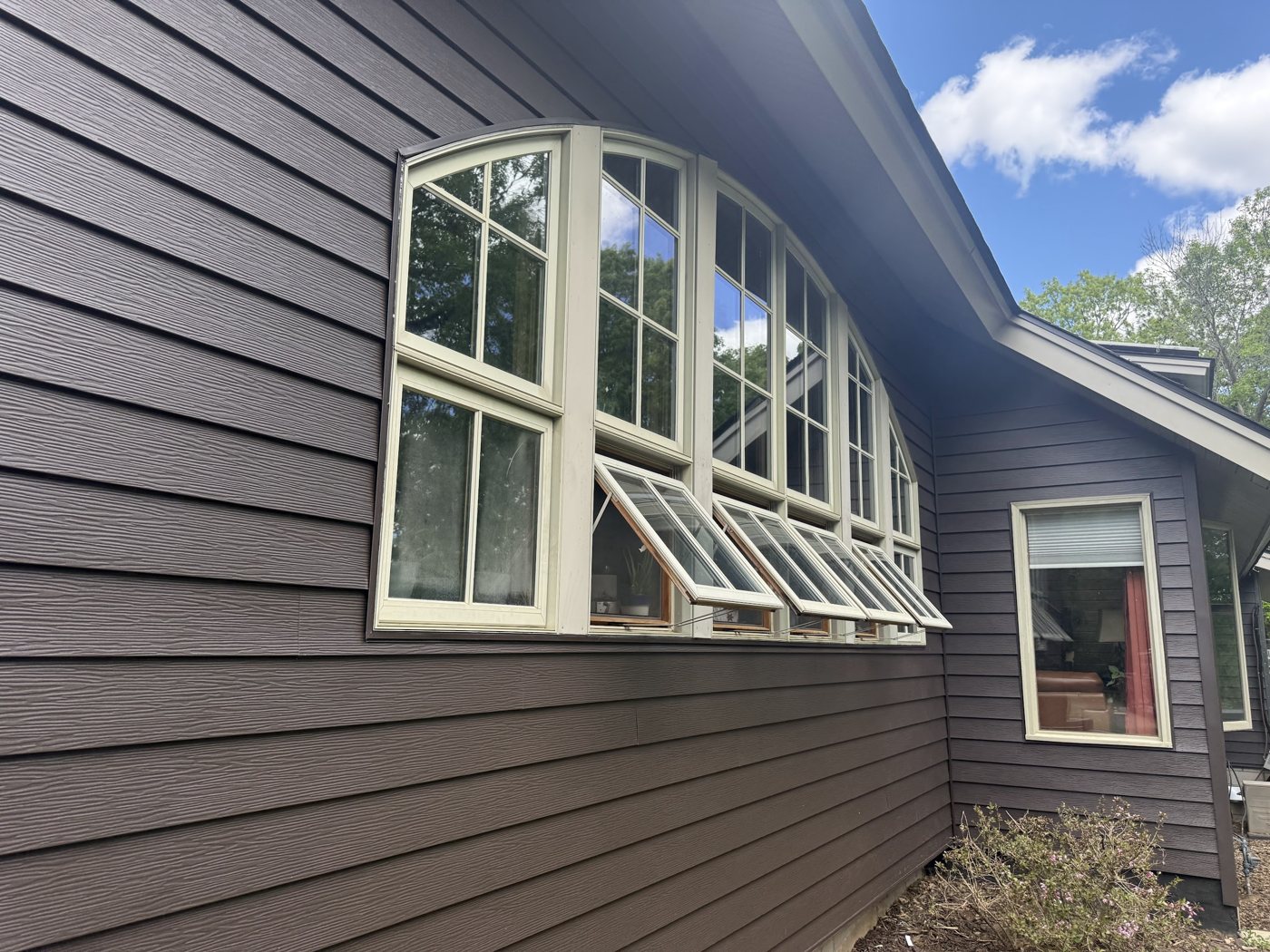 Repair King siding project — new dark lap siding around arched awning windows, Minnesota home