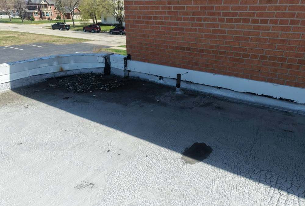 Cracked membrane and parapet flashing on a Lake City commercial flat roof, April 2026