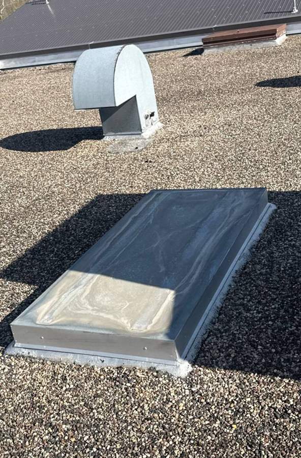 Domed skylight and exhaust vent on the gravel-ballasted roof at Safe Reflections, Greeley Street South, Stillwater, MN, April 2026