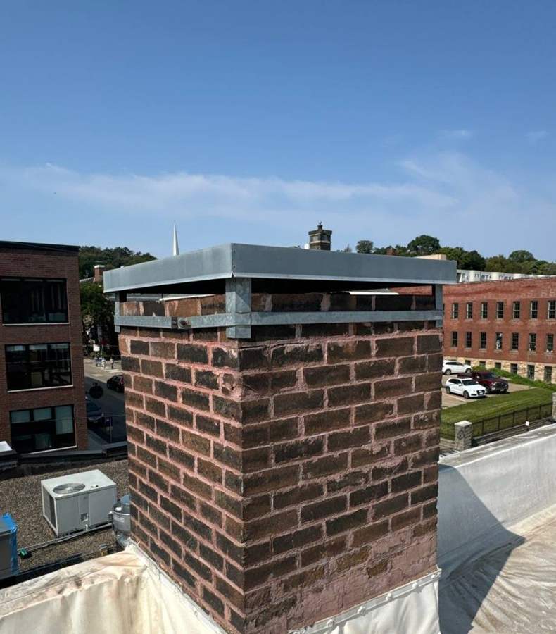 Brick chimney with a metal cap on the flat roof of 106 South Main Street in downtown Stillwater, MN, September 2024