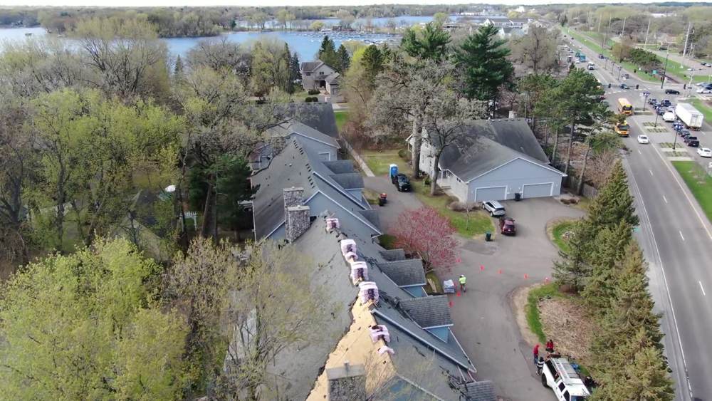 Looking down on a townhome roof and the tree-lined street during our White Bear Lake townhome project
