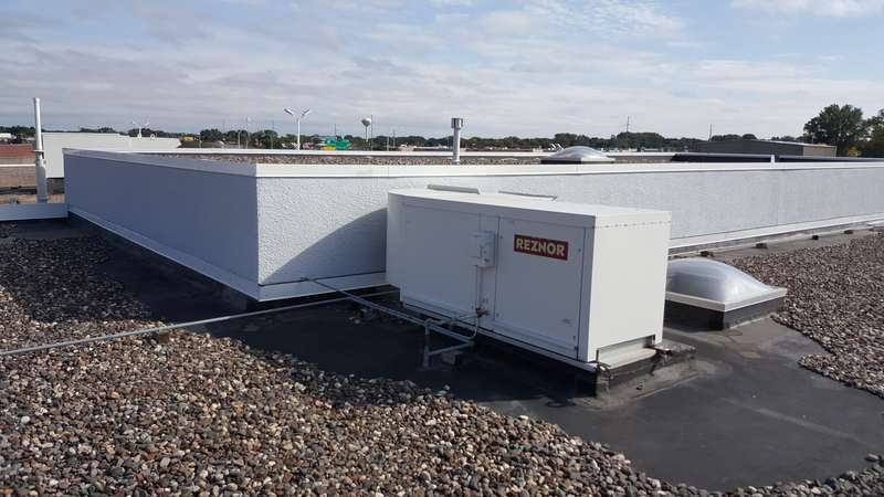 A rooftop unit and skylight on the old gravel roof at the Forest Lake dealership before the replacement