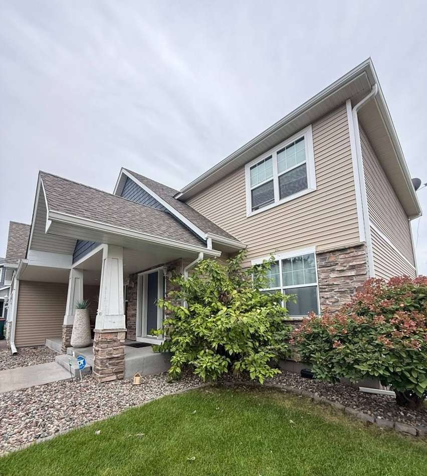 Two-story home with tan vinyl siding and a covered porch in Blaine, MN, September 2025