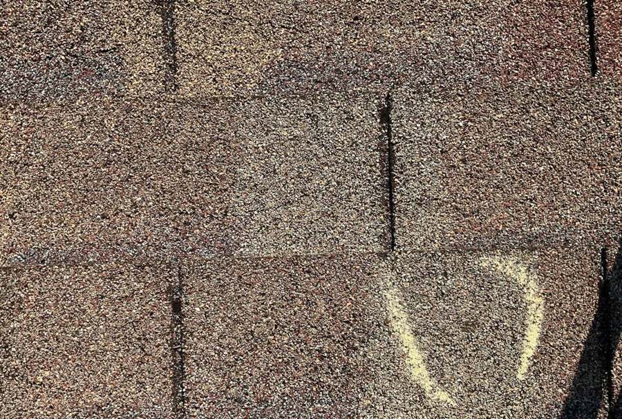 Hail hit chalk-marked and circled on a Montgomery shingle during an inspection, June 2023