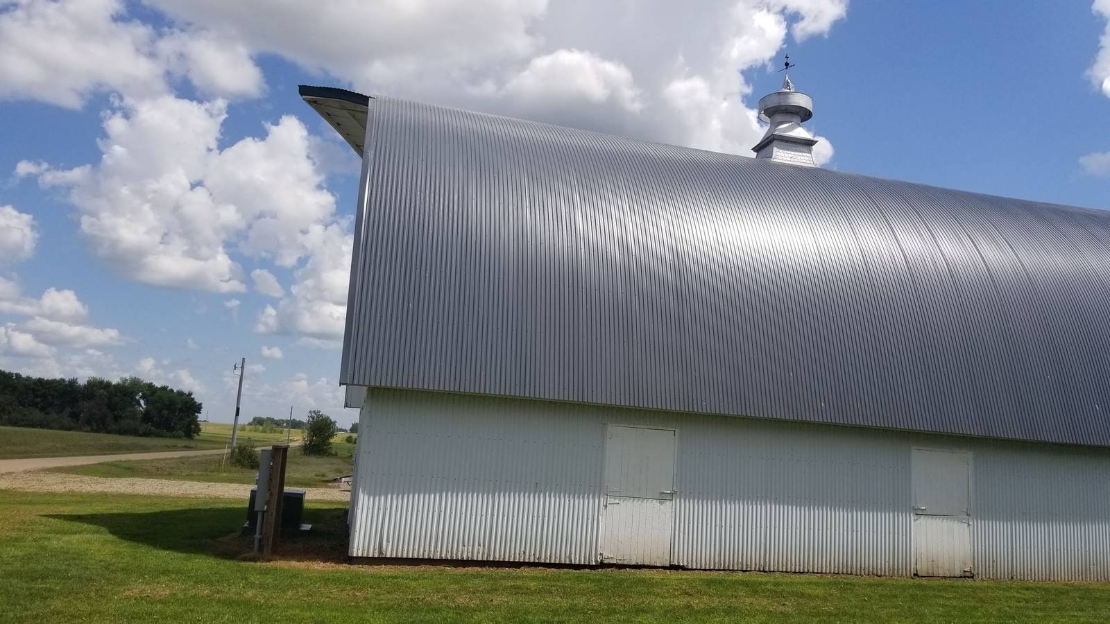 White barn with a gray arched steel roof and a metal cupola on a farm near Blue Earth, MN, photographed during a Repair King inspection