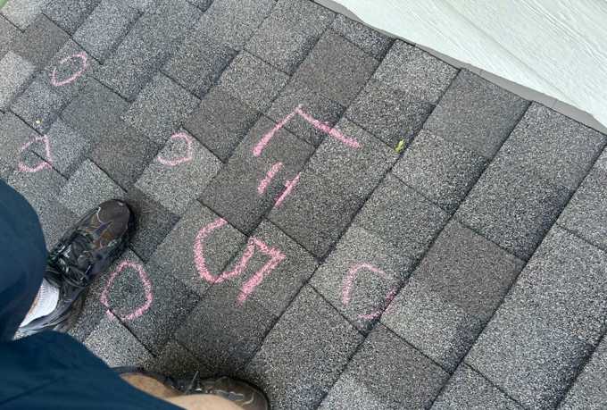 Pink chalk hail circles and a slope count written on a gray shingle roof on 4th Avenue in Newport, MN, September 2025