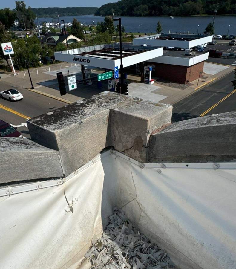 Stone parapet coping and flat roof membrane at 106 South Main Street, looking down on Main Street in downtown Stillwater, MN, September 2024
