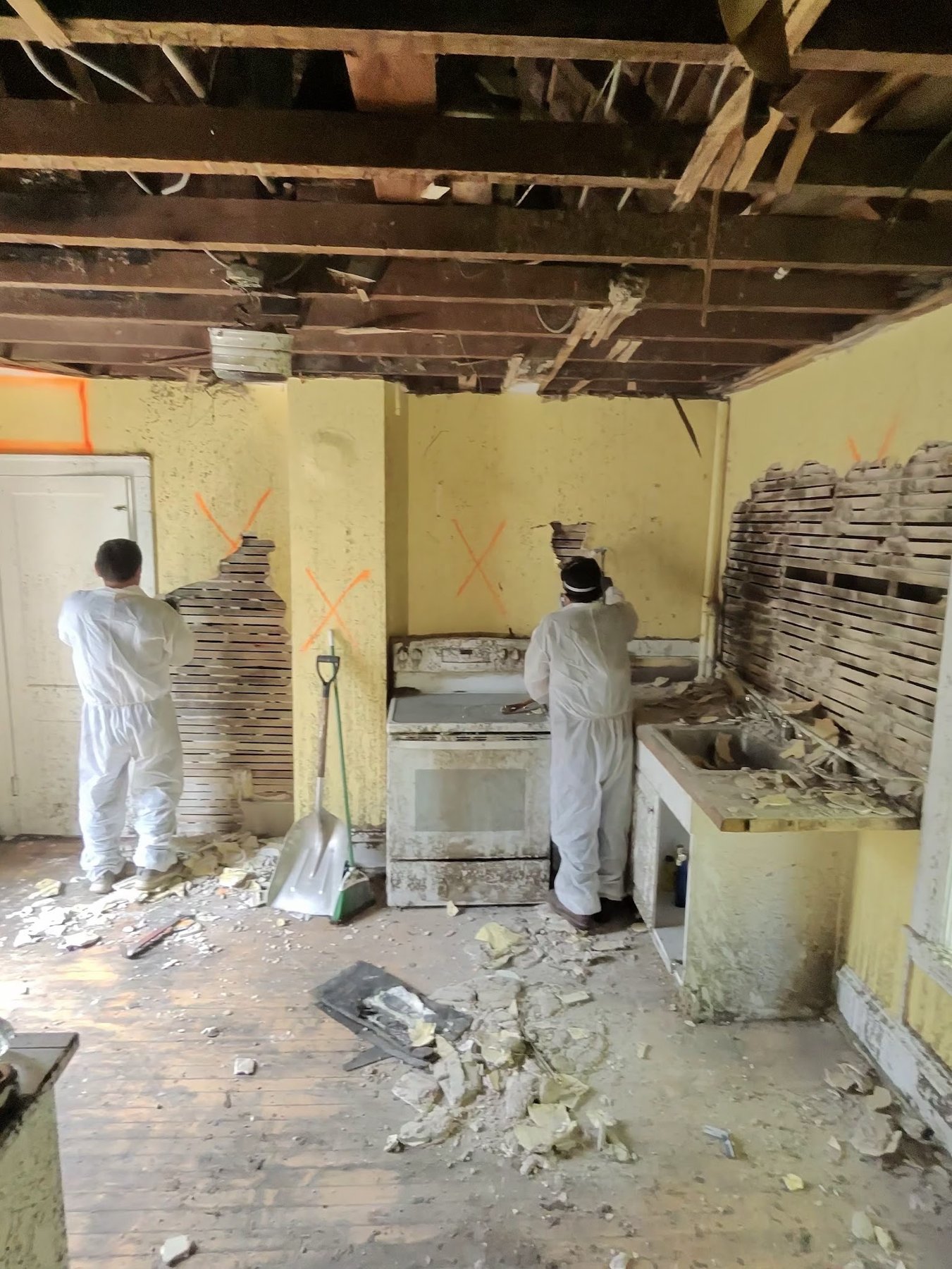 Crew removing marked plaster walls during fire tear-out