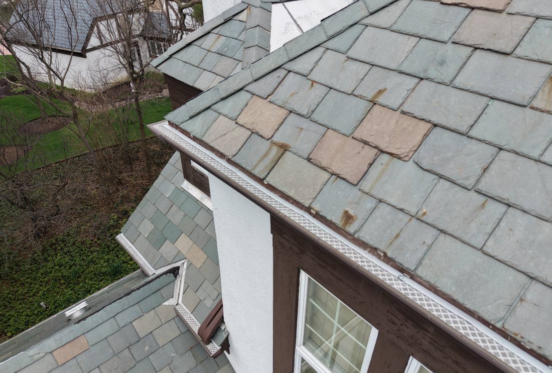 Close view of weathered, multi-color slate tiles on a Burr Ridge roof, April 2026