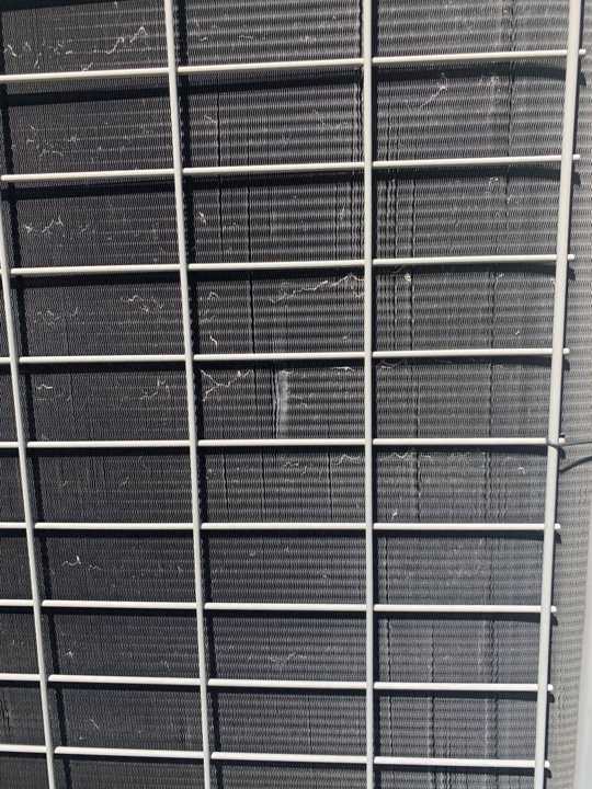 Close-up of the air-conditioner condenser fins at a Rockford home, a soft metal that shows hail dents, July 2020