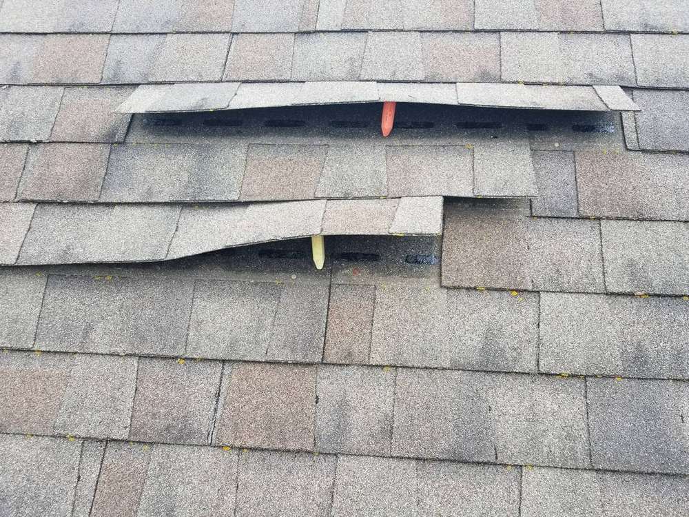 Wind-lifted and creased shingles on the Owatonna Country Club clubhouse roof in Owatonna, MN, with markers showing the lift