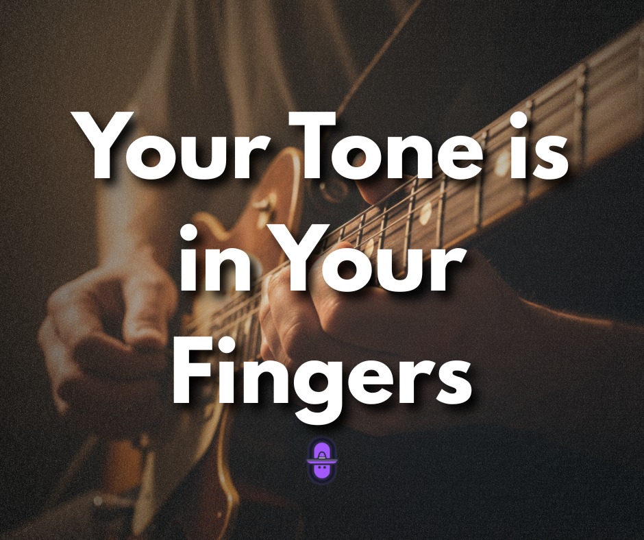 Close-up, moody shot of a guitarist's hands fretting a chord on an electric guitar with a sunburst finish. Bold white text centered on the image reads "Your Tone is in Your Fingers."