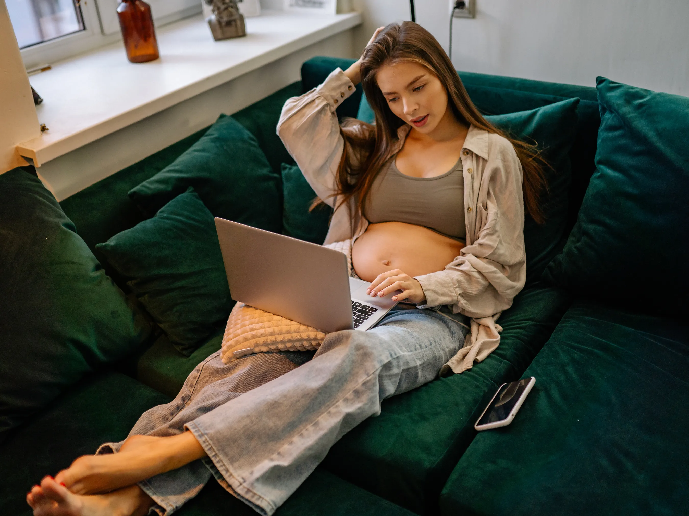 pregnant woman looking at baby shower ideas on laptop