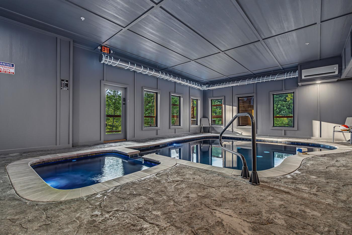 Indoor heated pool with blue ambient lighting and wooded views