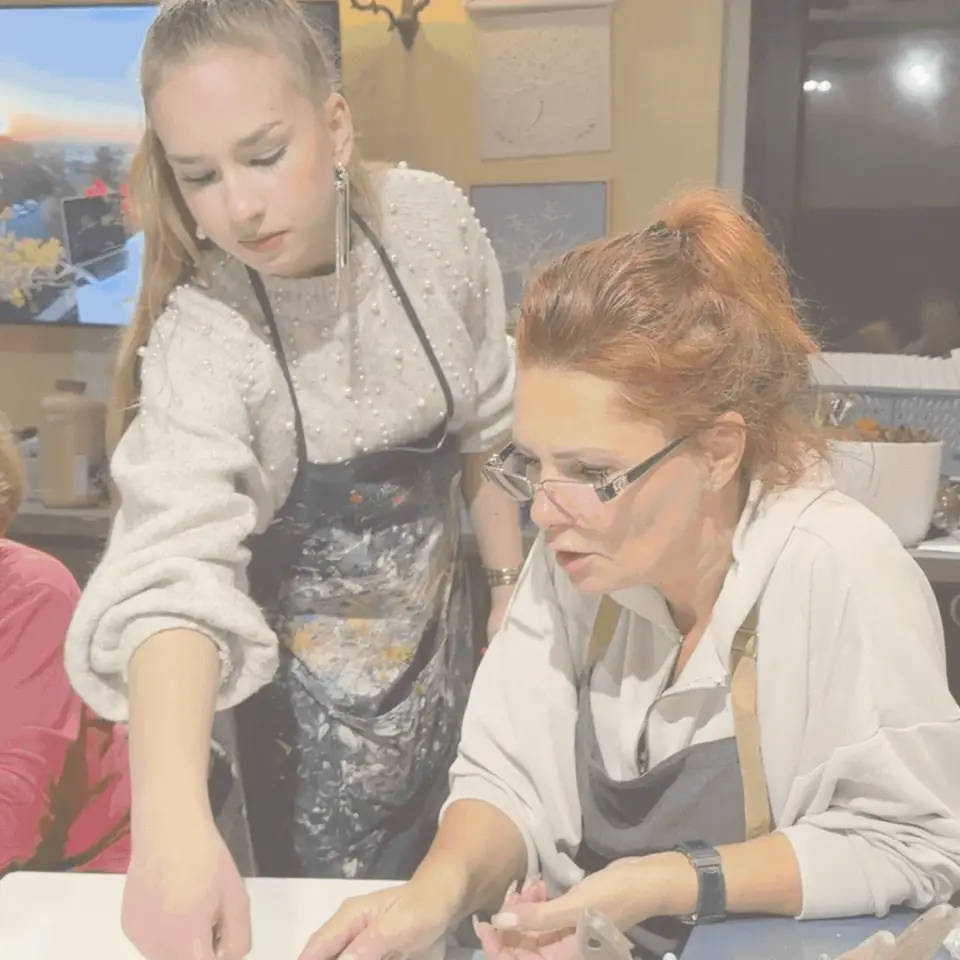 O instructoare Melinda Art care îi arată unei cursante cum să modeleze pasta de relief