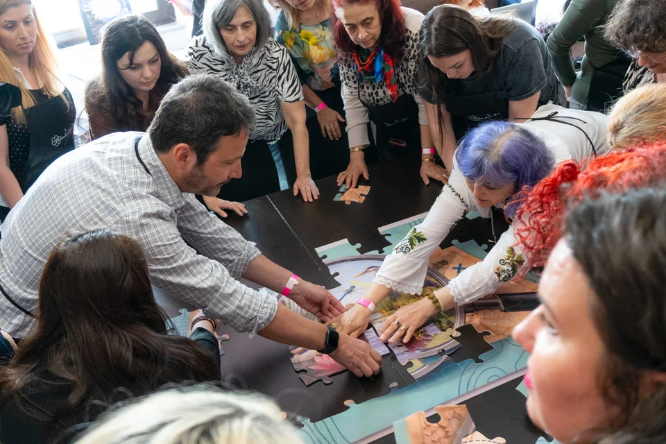 Colegi care asamblează tabloul colaborativ al echipei
