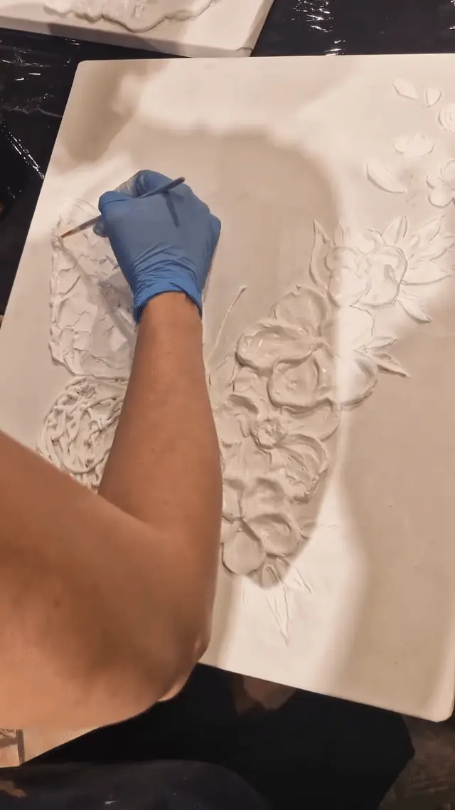 Mână care modelează pasta de relief, cu textura care iese din pânză