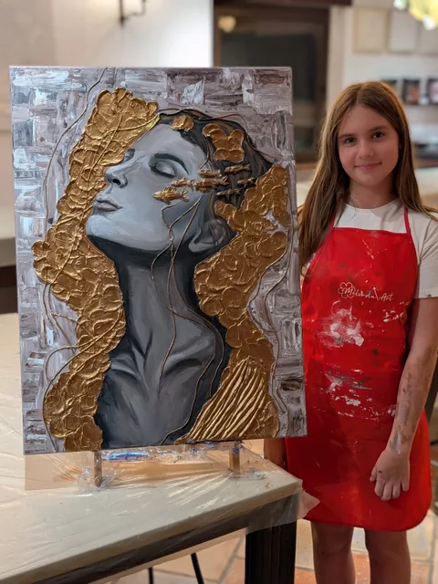 Fată la masterclass cu un portret în relief auriu