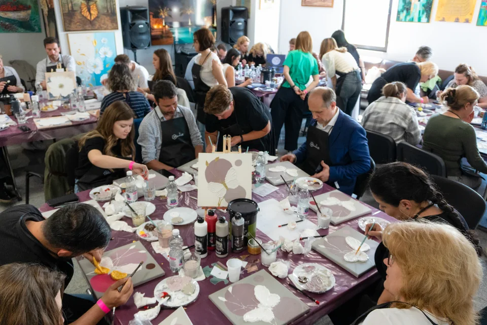 O sală plină de colegi care pictează împreună la un team building Melinda Art