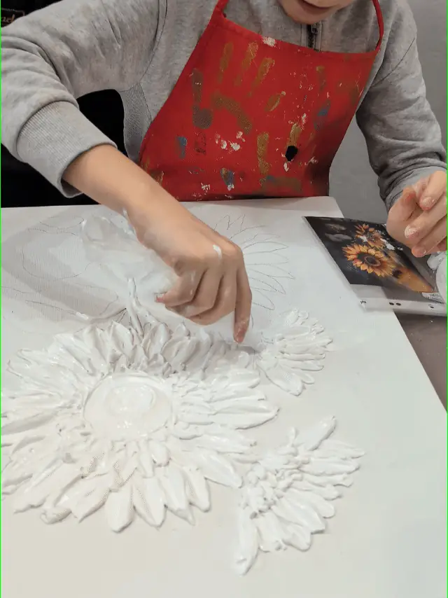 Mâna unui copil care modelează pastă de relief pe pânză
