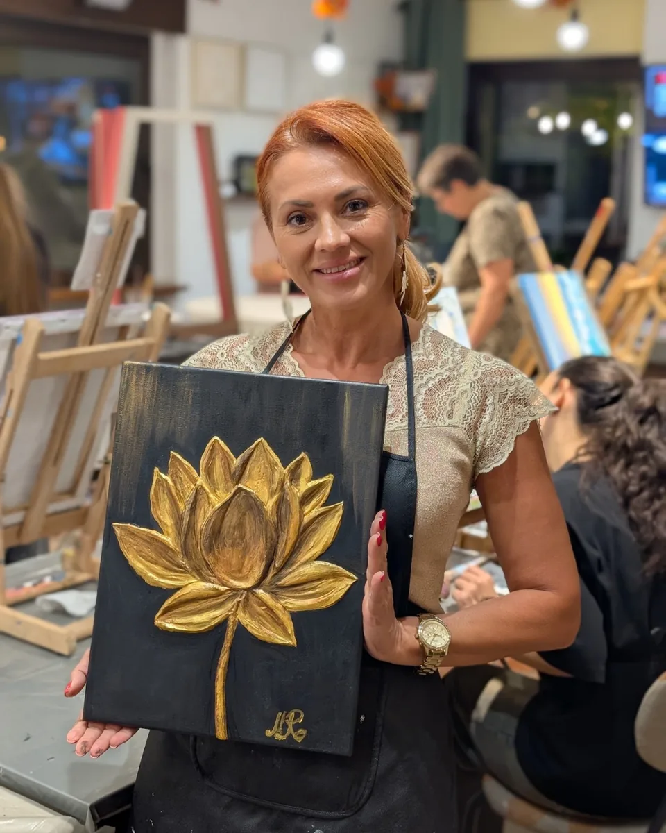 Cursantă zâmbind, cu primul ei tablou în relief: un lotus auriu pe fond închis