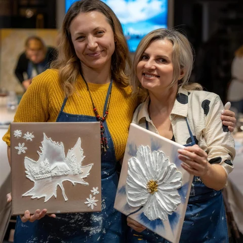 Două prietene la o seară tematică Melinda Art, cu tablourile lor în relief: o frunză de iarnă și o floare albă