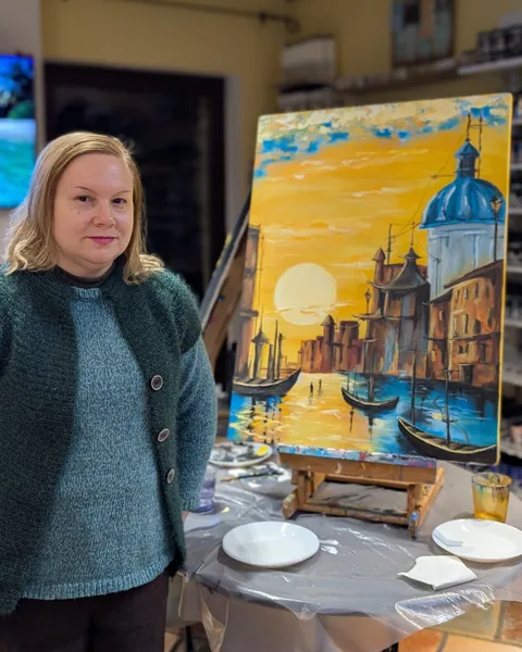 Mihaela, cursantă la masterclassul de natură, lângă tabloul ei cu un oraș pe apă la apus