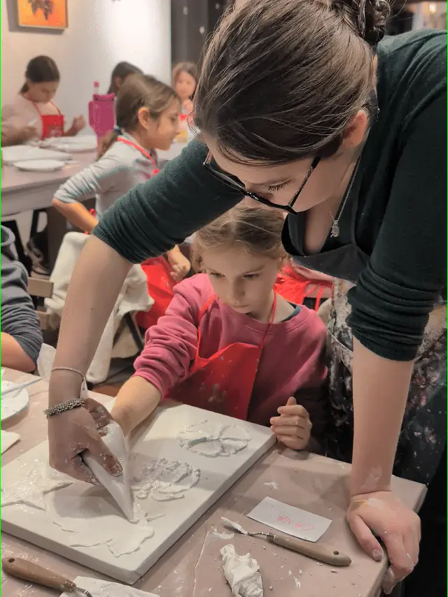 O profesoară Melinda Art care ghidează un copil la pictura în relief