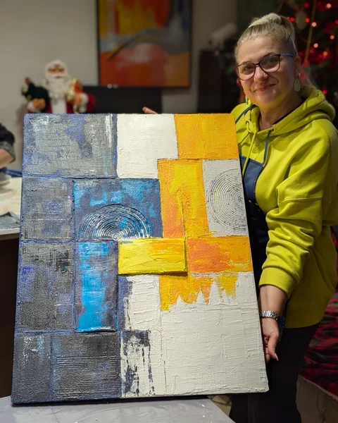 Cursantă la masterclass cu un tablou abstract în relief, galben și albastru