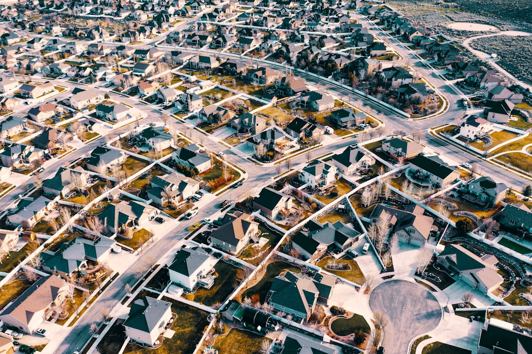 Aerial view of a suburban neighborhood of single-family homes with curving streets and cul-de-sacs in late afternoon light.