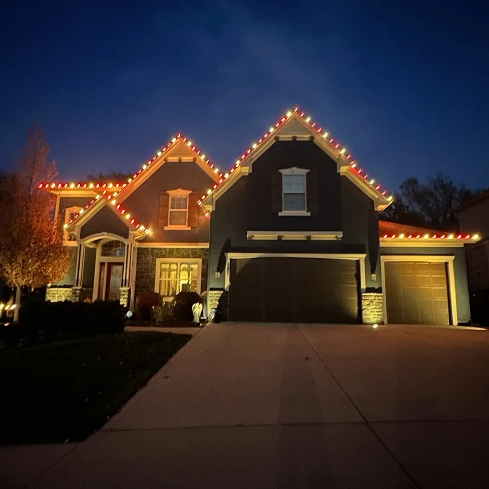 Red and green C9 bulbs tracing every peak of a two-story craftsman home at dusk